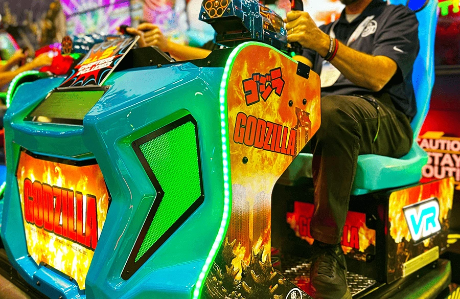 Player immersed in Godzilla VR shooting arcade game with vibrant LED lights and motion seat at Kuliku entertainment center
