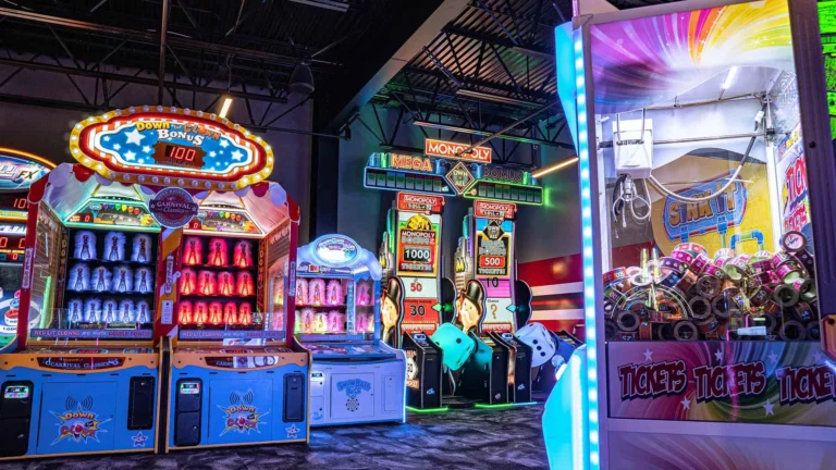 Row of colorful redemption arcade games including Connect 4 Hoops basketball, Skee Ball, and ticket jackpot machines in a modern Kuliku entertainment center