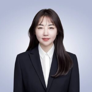 Smiling Asian woman wearing a black blazer and white shirt with a professional appearance, against a light blue gradient background.