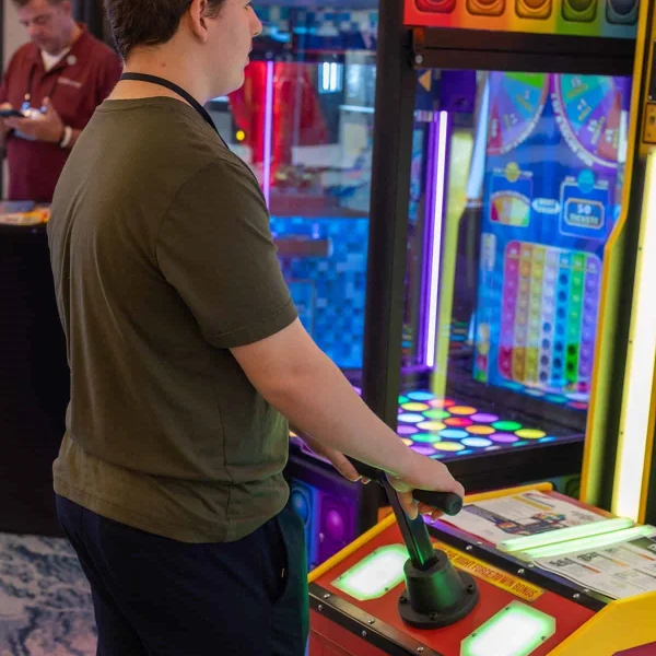 Player operating an interactive arcade push-button game machine with illuminated control panel