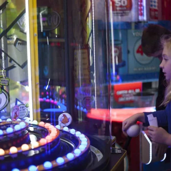 Young girl excitedly playing ball toss redemption arcade game with bonus shot up to 1000 tickets at Kuliku arcade