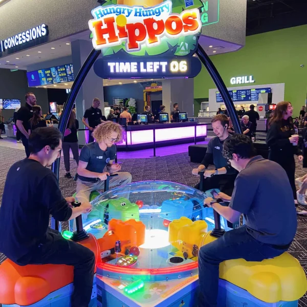 Group of friends enjoying the classic Hungry Hungry Hippos multiplayer arcade game in a vibrant Kuliku entertainment center